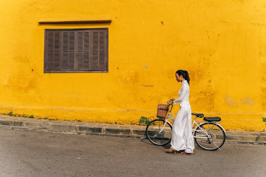 A Woman in White Ao Dai Walking with a Bicycle